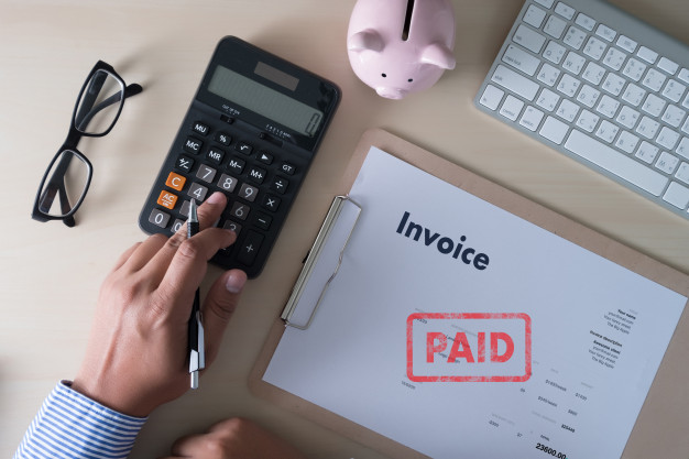 invoice paid image, man using a calculator invoice with paid stamp