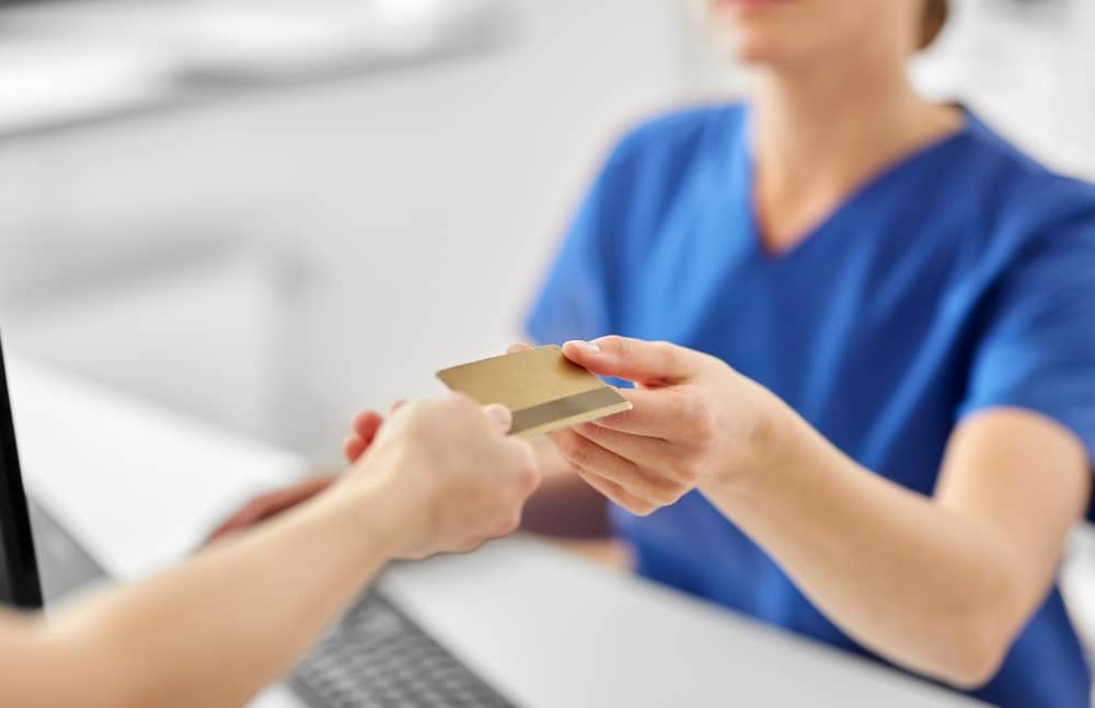 Handing health insurance card to nurse.